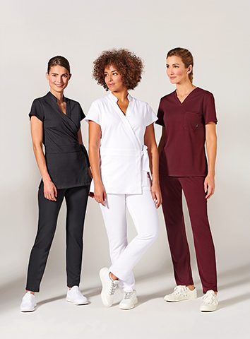 Trois femmes portant des uniformes médicaux de différentes couleurs.